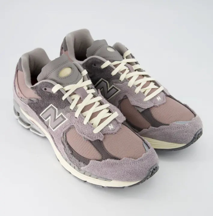 Zapatillas New Balance 2002R Protection Pack color lila y malva con paneles de ante desgastados.