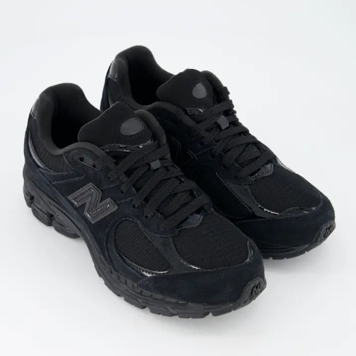 Zapatillas New Balance 2002R hombre color Triple Black con detalles en ante y malla negra.