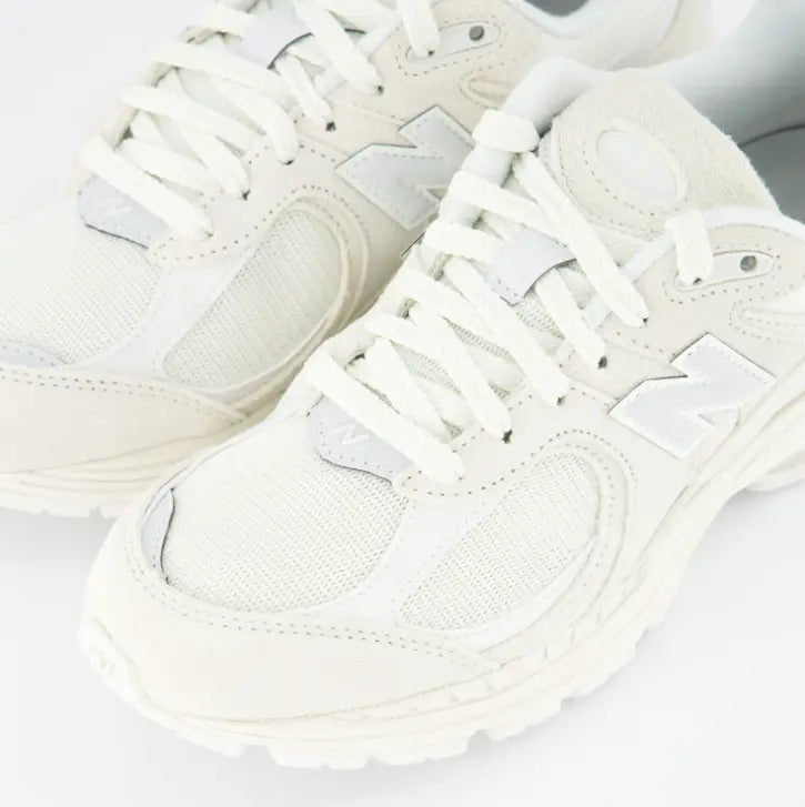 Primer plano New Balance 2002R mostrando paneles de malla transpirable y logo N reflectante.