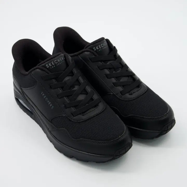 zapatillas Skechers Hands Free Slip-ins Uno en color negro total, con malla transpirable, cordones decorativos fijos y suela con cámara de aire visible.