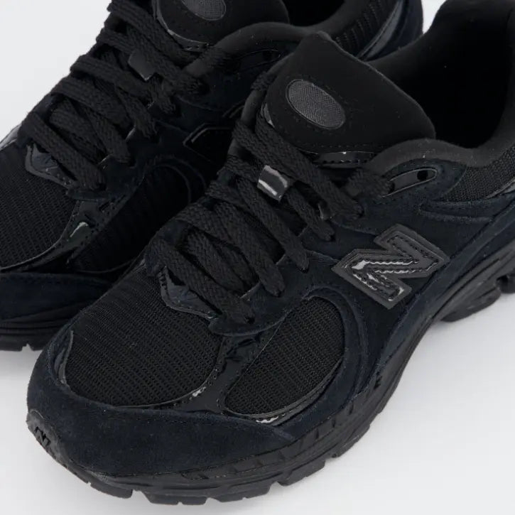 Detalle de materiales premium New Balance 2002R con texturas de ante, piel sintética y malla negra.